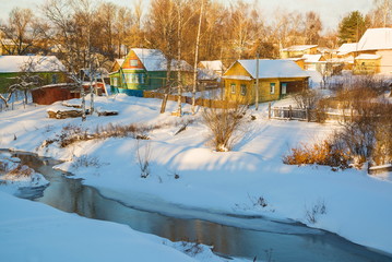 Winter snow-covered village on the banks of the river