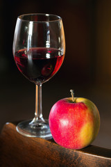 glass of wine and an apple on a wooden board