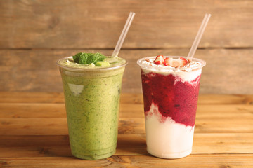 Delicious kiwi and strawberry milkshakes on wooden background