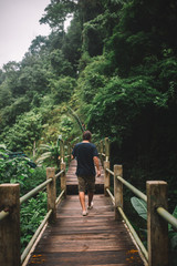 Young traveler crossing the bridge under the river in the jungle, Indonesia, Bali
