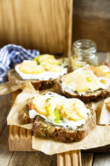 Sandwiches from homemade bread with pumpkin seeds, goat cheese, apple and onion
