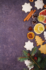Obraz na płótnie Canvas Christmas background with gingerbread cookies, dried citrus and fir tree. Decorations and gift box on rustic wooden board. View from above, top studio shot