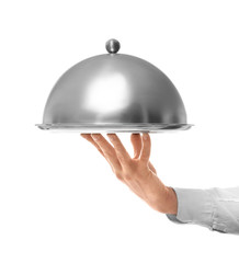 Hand of waiter holding metal tray with cover on white background