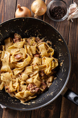 Pappardelle pasta with prosciutto and cheese sauce on pan