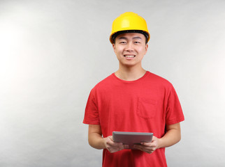 Asian warehouse worker with tablet computer on light background