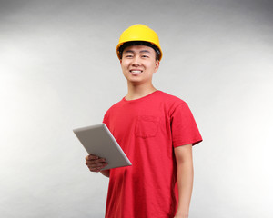 Asian warehouse worker with tablet computer on light background
