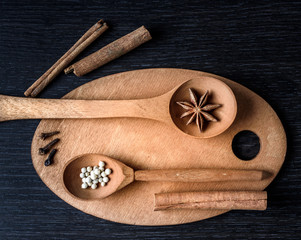 set of wooden utensils with star anise pepper cinnamon isolated on dark background