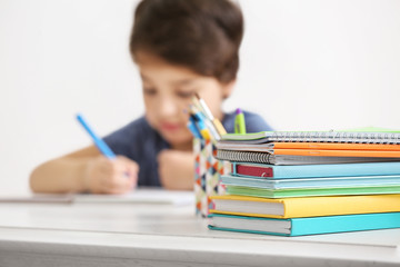 Color notebooks and books on blurred boy background, close up