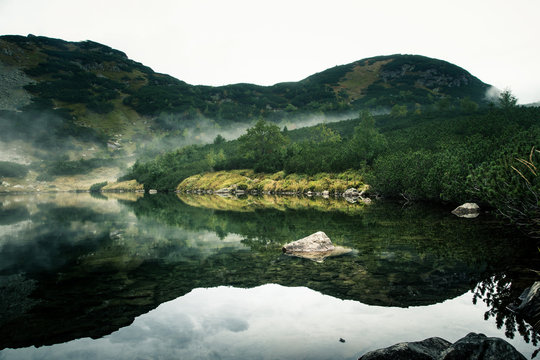 Fototapeta A beautiful mountain lake in a fog in Tatry, Slovakia. Low saturation retro style