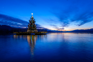 Christmas tree floating on a lake after sunset.