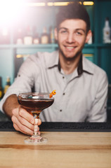 Young Barman offers alcohol cocktail in night club bar