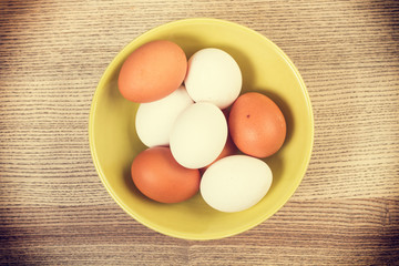 Huevos de Gallina colorados y blancos en un cuenco verde sobre mesa de madera rústica. Vista...