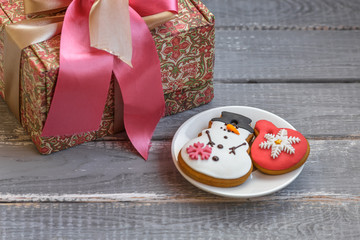 Handmade gift box and homemade gingerbreads on a plate on wood rustic table. 