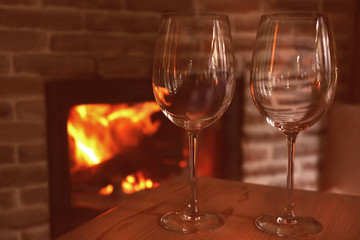 Wine glasses on wooden table against fireplace