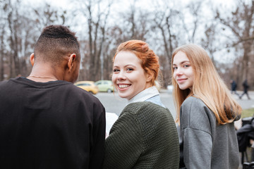 Group of young smiling teenagers sitting together outside