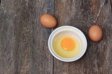 Raw egg in a bowl selective focus on wooden table
