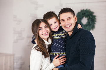 Family of mother, father and little child near Christmas tree with presents, decorations and New Year or Christmas