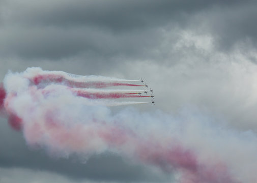 Air force pilots flying in formation on a dramatic cloudy sky. Colorful smoke trail.