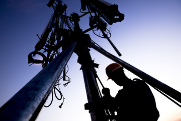 Silhouette of Technician working on communication towers in the dusk