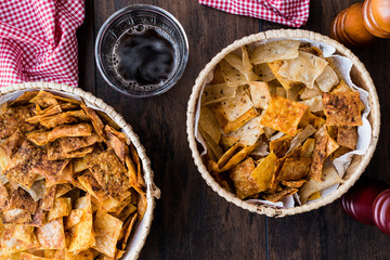Homemade Crispy Chips / Snacks in a wicker bowl with beverage