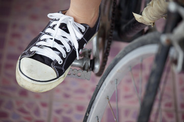 Naklejka premium Person riding a vintage bicycle, close up view of sneaker shoe a