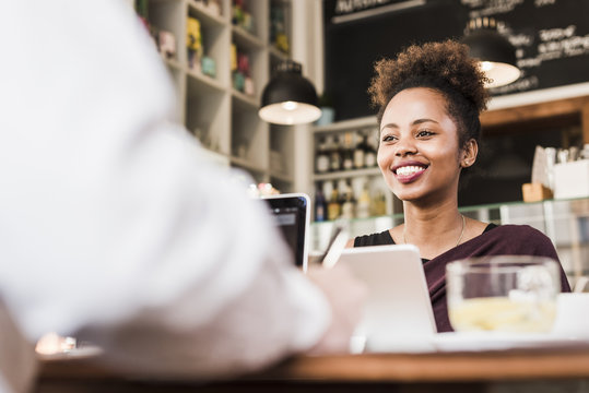 Waitress at counter in a cafe smiling at customer