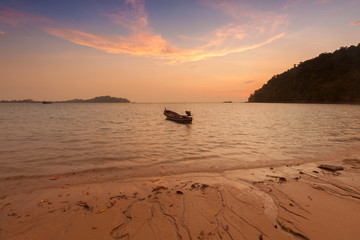 Wooden boat on a beach at sunset.