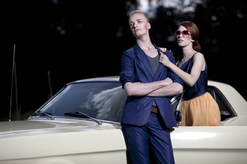 Pärchen trägt 50er / 60er Jahre retro Fashion vor einem Mustang Oldtimer