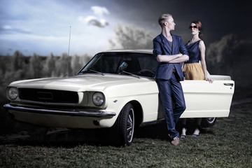 Pärchen trägt 50er / 60er Jahre retro Fashion vor einem Mustang Oldtimer