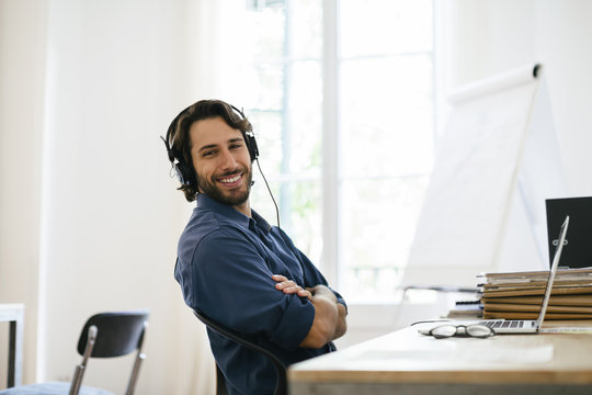 Businessman in office using headphones at desk