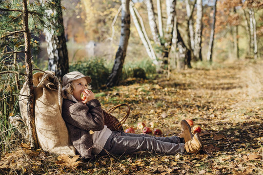 Hansel and Gretel, Boy leaning against tree in forest, eating apple