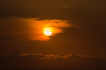 Sun setting through a thin veil of high cirrus clouds