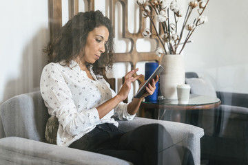 Businesswoman sitting in lounge using digital tablet