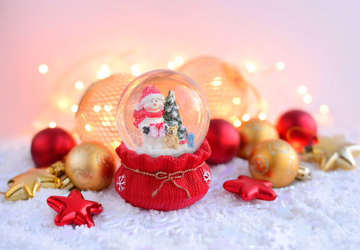 A snow globe with snowman with Christmas decorations and Christmas lights. Festive Christmas background