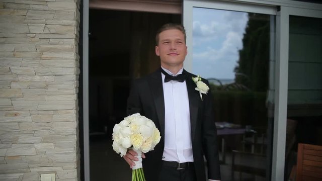 Happy groom is waiting for his bride. Young man waiting for his bride in outdoor wedding in sunny summer day.