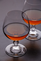 Two glasses of brandy on a dark table