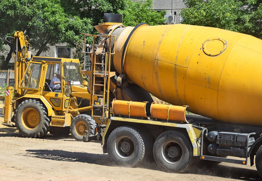 Cement mixer truck and excavator at the construction site