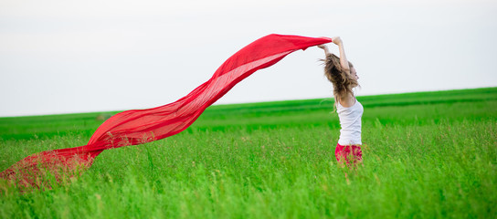Young lady runing with tissue in green field. Beautiful happy woman walking  in the summer rural meadow. Outdoor summer portrait of pretty sport style woman jumping with fabric. Beautiful fit tan girl