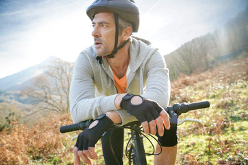 Fototapeta premium Mature man riding bike in the mountain