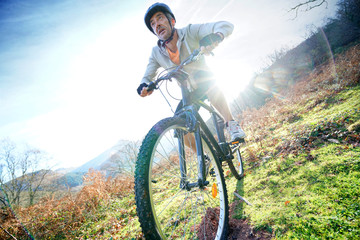 Fototapeta na wymiar Mature man riding bike in the mountain