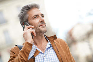 Mature handsome man in the street, talking on phone