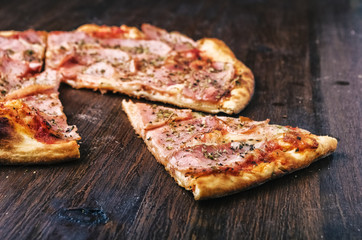 Slice of pizza with ham and cheese on wood table