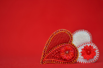 Red and white beaded jewelry hearts on red textile background