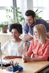 happy creative team with computer in office