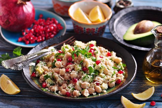 Salad of sprouted chickpeas with couscous, avocado, parsley, olive oil and pomegranate