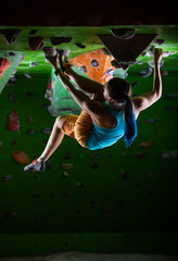 Young woman bouldering on ceiling in climbing gym