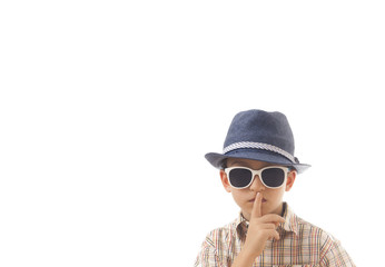 Caucasian kid with hat and sunglasses. Isolated on white background. Space for copy or other design.Keep quiet concept.