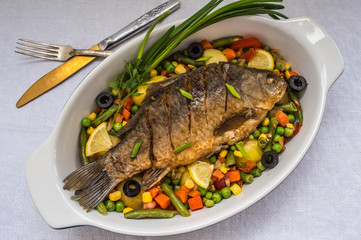 Grilled fish on brown plate with herbs and lemon  white background, top view. Mediterranean luxurious seafood concept.