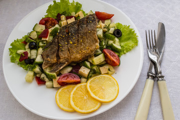 Fried fish fillet on a bed of Caesar salad. Wooden background. Top view.