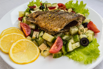 Fried fish fillet on a bed of Caesar salad. Wooden background. Top view.